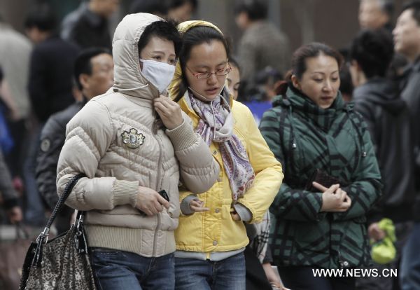 People are seen in thick clothes in a street in Shanghai, east China, Dec. 6, 2010. Many places in China witnessed strong wind and significant temperature drop due to a cold wave.[Xinhua]
