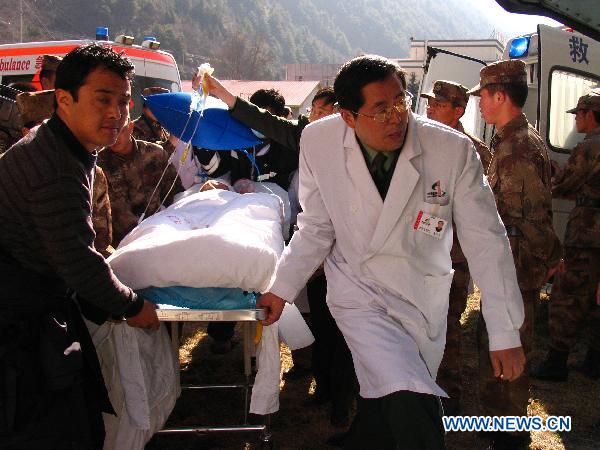 Paramedics transfer an injured man onto a helicopter in Kangding, southwest China&apos;s Sichuan Province, Dec. 6, 2010. Four injured people in the wild fire in Daofu County have been transfered to the hospitals in Chengdu by helicopters to receive further medical treatment on Monday. [Xinhua] 