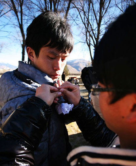 Young people put on white flowers to mourn the firefighters who gave their lives putting out a wildfire on plateau grassland in Dawu county, Southwest China&apos;s Sichuan province, Dec 6, 2010. [Xinhua] 