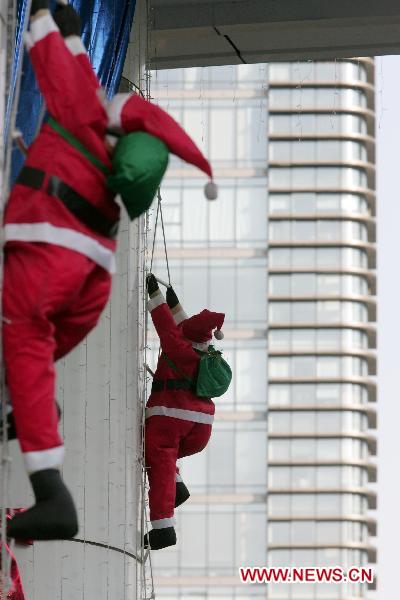 Two Santa Clauses are clinging to a skyscraper in Hangzhou, capital of east China&apos;s Zhejiang Province, Dec. 7, 2010. Some Santa Clauses were clinging to the skyscraper to attract passers-by before the Christmas Day. [Xinhua]