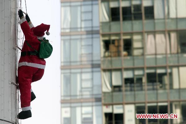 A Santa Claus is clinging to a skyscraper in Hangzhou, capital of east China&apos;s Zhejiang Province, Dec. 7, 2010. [Xinhua]