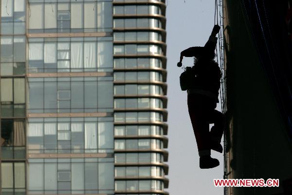 A Santa Claus is silhouetted on a skyscraper in Hangzhou, capital of east China&apos;s Zhejiang Province, Dec. 7, 2010. [Xinhua] 