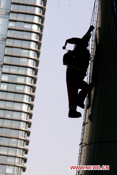 A Santa Claus is silhouetted on a skyscraper in Hangzhou, capital of east China&apos;s Zhejiang Province, Dec. 7, 2010. [Xinhua]