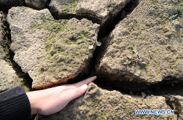 A man inserts his hand into dried riverbed of the Ganjiang River in Nanchang, east China's Jiangxi Province, Dec. 7, 2010. Water levels of main rivers and lakes in Jiangxi continuously dropped due to the rainfall decrease which happened since late October. About 230 thousand residents in the range of the province, especially in the cities along the Ganjiang River such as Nanchang, Fengcheng, Zhangshu, are suffering from the lack of drinking water. 