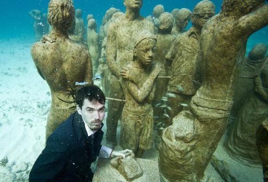 Young people dressed in everyday wear, dive amongst the statues at the underwater art installation, Silent Evolution in Cancun, Mexico, on Dec. 6, 2010. TckTckTck partners, Greenpeace and 350.org, staged a haunting underwater tableau to highlight the need for urgent action as the UN Cancun climate talks went into their second week. [Photo: Xinhua] 