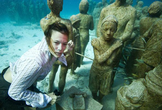 Young people dressed in everyday wear, dive amongst the statues at the underwater art installation, Silent Evolution in Cancun, Mexico, on Dec. 6, 2010. TckTckTck partners, Greenpeace and 350.org, staged a haunting underwater tableau to highlight the need for urgent action as the UN Cancun climate talks went into their second week. [Photo: Xinhua] 