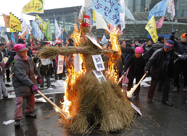 South Korean farmers burn an effigy representing the US-South Korea Free Trade Agreement at a rally in Seoul Dec 8, 2010. [China Daily/Agencies]