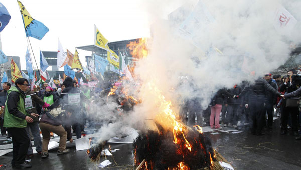 South Korean farmers burn an effigy representing the US-South Korea Free Trade Agreement at a rally in Seoul Dec 8, 2010. [China Daily/Agencies]