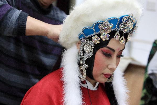 Xing Meizhu from Heilongjiang Peking Opera Troupe has makeup applied backstage prior to performing &apos;Lu Gou Xiao Yue&apos; (the moon at dawn in Lu Gou) in Beijing, capital of China, Dec. 8, 2010. The show reflects the life and culture of the Nuzhen people, an ancient nationality in China. Wednesday is the second day of the month-long demonstration of excellent Peking Opera plays in Beijing. [Xinhua]