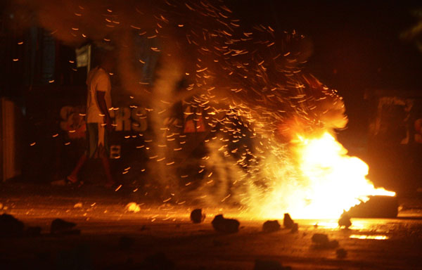 A man walks past tyres being burnt as part of a barricade during a protest against the provisional electoral council decision to hold a presidential run-off in Port-au-Prince December 7, 2010. [Xinhua]