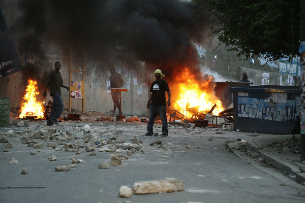 Protesters stand next to a burning barricade during a protest following presidential elections in Port-au-Prince December 8, 2010. [Xinhua]