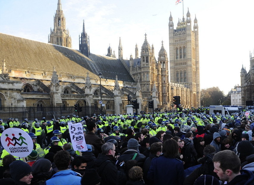 Policemen whose shields were spilled with paint thrown by protesters stand guard in front of the Parliament Building in London, Britain, Dec. 9, 2010. [Xinhua]