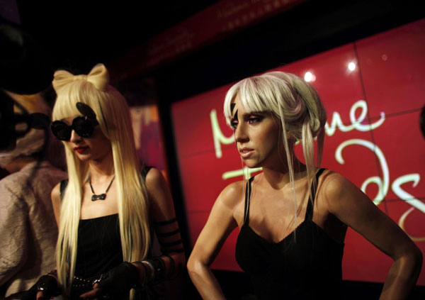 A model talks with reporters during the unveiling of pop singer Lady Gaga&apos;s wax statue (R), in a short black Orchel-Read trousers with black top, thigh high patent boots and black lightning stripe make up over one eye, at the Madame Tussauds Wax Museum in Shanghai, Dec 9, 2010. Shanghai joins seven other Madame Tussauds attractions around the world revealing new Lady Gaga figures on Thursday. [China Daily/Agencies] 