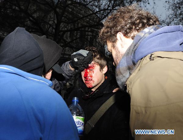 An injured protester is taken care of by his friends in London, Britain, Dec. 9, 2010. Over 20,000 students took to streets to protest against the coalition government's plan to raise the tuition fees cap in England from 3290 to 9,000 pounds per year, which was passed in the House of Commons Thursday. More than a dozen of policemen and students have been injured during the clash. [Zeng Yi/Xinhua]