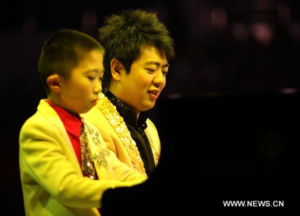 Renowned Chinese young pianist Lang Lang (R) together with a child performs during his new year concert in Nantong, east China's Jiangsu Province, Dec. 10, 2010. [Huang Zhe/Xinhua]