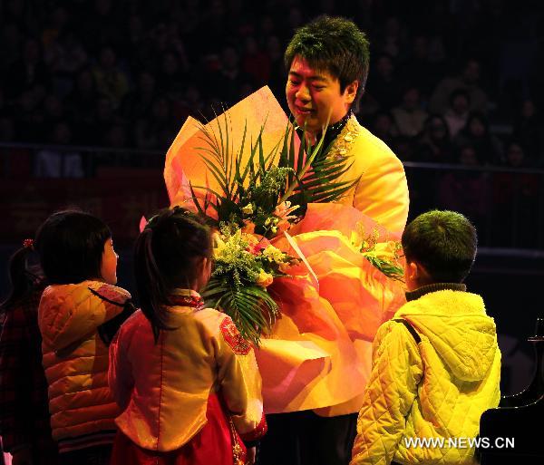 Children present flowers to renowned Chinese young pianist Lang Lang during his new year concert in Nantong, east China's Jiangsu Province, Dec. 10, 2010. [Ding Xiaochun/Xinhua]
