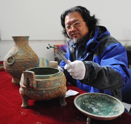 Archaeologist Liu Daiyun extracts an animal bone from the soup contained in a 2,400-year-old bronze tripod unearthed in an ancient tomb in Xi'an, capital of Northwest China's Shaanxi province, Dec 10, 2010. [Xinhua]