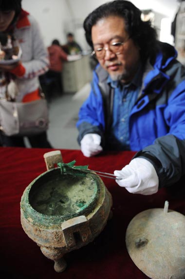 Archaeologist Liu Daiyun extracts an animal bone from the soup contained in a 2,400-year-old bronze tripod unearthed in an ancient tomb in Xi&apos;an, capital of Northwest China&apos;s Shaanxi province, Dec 10, 2010. [Xinhua]