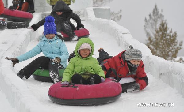 Children ride ice slides at the opening ceremony of the Genhe snow festival in Genhe, north China&apos;s Inner Mongolia Autonomous Region, Dec. 12, 2010. The annual snow festival kicked off here Sunday as temperature in Genhe hit as low as minus 45 degrees Celsius. [Xinhua]