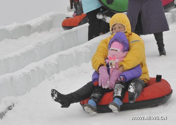 A mother and her child plays in the snow in Genhe, north China&apos;s Inner Mongolia Autonomous Region, Dec. 12, 2010. Temperature in Genhe hit as low as minus 45 degrees Celsius on Sunday, according to local meteorological authorities. A sharp temperature drop of more than ten degrees Celsius, caused by recent cold snaps, was recorded in the Inner Mongolian city. [Xinhua]