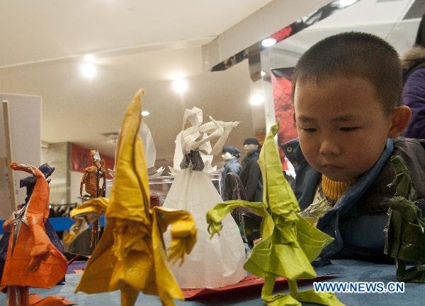 A child appreciates paper folding works during an exhibition in Hangzhou, capital of east China&apos;s Zhejiang Province, Dec. 11, 2010. Some 150 paper folding works created by more than 20 makers were displayed here on Saturday. [Xinhua] 