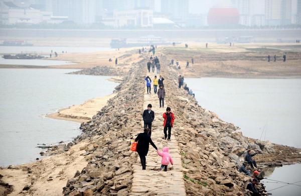 People walk on the dam in Gangjiang river in Nanchang, East China&apos;s Jiangxi province, Dec 11, 2010. The water level of the province&apos;s largest river reduced to a historical low of 12.89m. [Xinhua] 