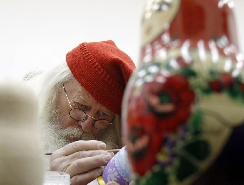 A man dressed as Julenissen, Norway&apos;s Santa Claus, paints a wooden &apos;Matryoshka&apos; doll as he takes part in Christmas festivities in Moscow Dec 7, 2010.[China Daily/Agencies] 