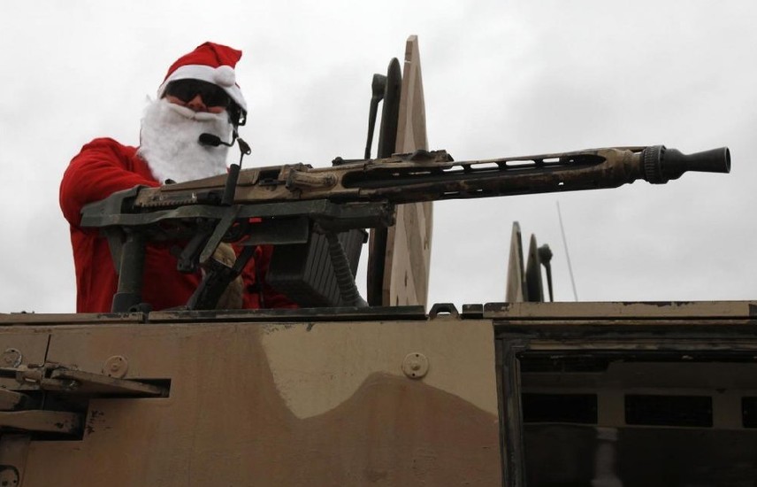 A German Bundeswehr army soldier with the Delta platoon of the 2nd paratroop company 373 wearing a Santa Claus costume stands atop an armoured vehicle before leaving the army camp for a mission in Kunduz, northern Afghanistan, Dec 6, 2010. [China Daily/Agencies] 