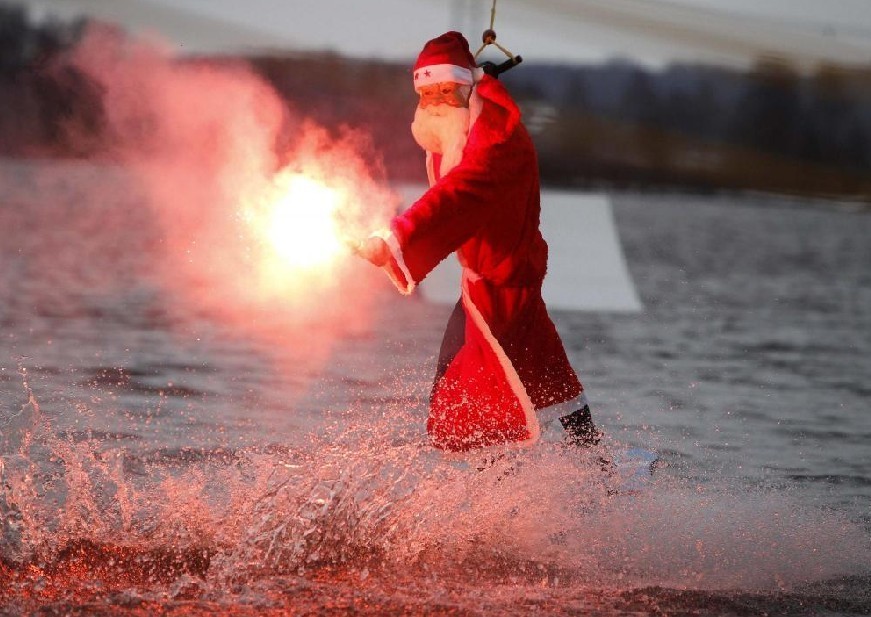 A man dressed as Santa Claus holds a flare as he wakeboards at a water ski set on a small lake in Hamburg Dec 5, 2010.[China Daily/Agencies] 