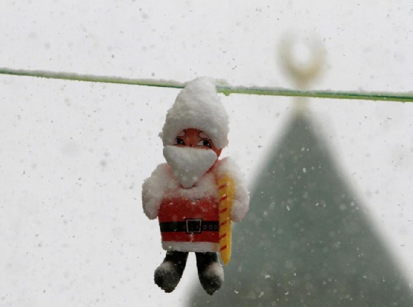 A Santa Claus figurine is covered with snow after a storm hit the front of a mosque at Bahamdoun village in eastern Lebanon, Dec 12, 2010. [China Daily/Agencies]