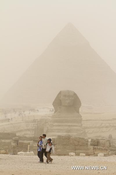 Boys walk in front of the Sphinx during the dust storm in Cairo, capital of Egypt, Dec. 12, 2010. 