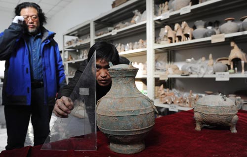 An archaeological worker measures a bronze pot unearthed in an ancient tomb in Xi'an, capital of Northwest China's Shaanxi province, Dec 10, 2010. [Photo/Xinhua] 