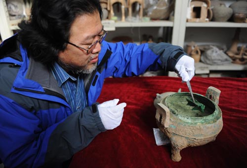Archaeologist Liu Daiyun extracts an animal bone from the soup contained in a 2,400-year-old bronze tripod unearthed in an ancient tomb in Xi'an, capital of Northwest China's Shaanxi province, Dec 10, 2010. [Photo/Xinhua] 