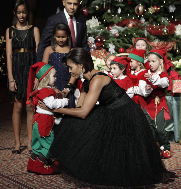 U.S. first lady Michelle Obama greets a child dressed as an elf at the Christmas in Washington Celebration at the National Building Museum in Washington December 12, 2010. U.S. President Barack Obama and their daughters Malia (L) and Sasha are seen in the background. [Xinhua/Reuters] 