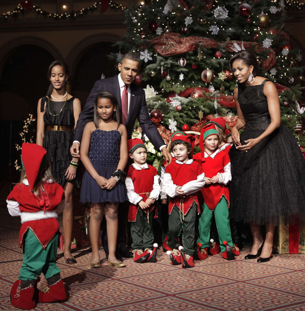 U.S. President Barack Obama, first lady Michelle Obama and their daughters Malia (L), Sasha (2nd L) greet children dressed as elves at the Christmas in Washington Celebration at the National Building Museum in Washington December 12, 2010. [Xinhua/Reuters]