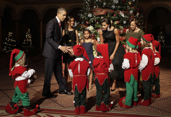 U.S. President Barack Obama with first lady Michelle Obama, their daughters Malia (2nd L), Sasha (3rd L) and Michelle Obama&apos;s mother Marian Robinson (R) greet children dressed as elves at the Christmas in Washington Celebration at the National Building Museum in Washington December 12, 2010. [Xinhua/Reuters] 