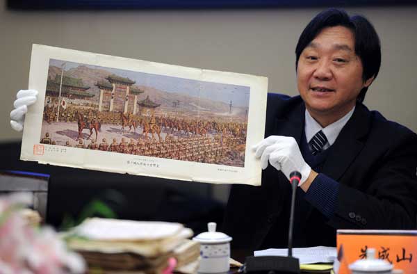 Zhu Chengshan, curator of the Memorial Hall of the Victims in the Nanjing Massacre by the Japanese Invaders in Nanjing, on Monday displays a painting featuring the Japanese army entering the city - then the capital of China - in December 1937. The memorial hall recently received 17 war relics donated by a Japanese man surnamed Ohigashi. [Photo/Xinhua] 