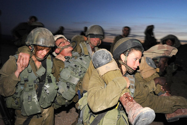 Female Israeli Defense Force (IDF) soldiers carry the &apos;wounded&apos; during a drill in a desert near Israel-Egypt border and Israeli Southern City of Sede Boker, on Dec 13, 2010.[Xinhua]