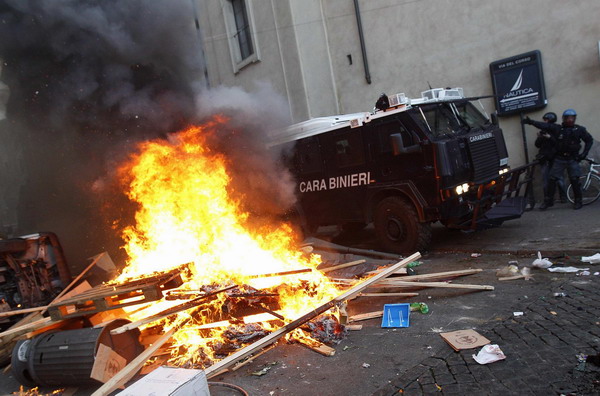 A Carabinieri vehicle passes through a fire during anti-government clashes near the parliament in Rome December 14, 2010. [China Daily/Agencies]