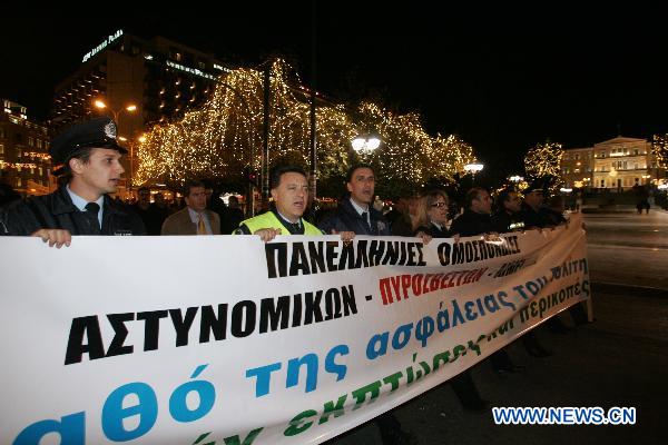 Greek police officers raise a banner that says 'Enough is enough with cuts on salaries' during a rally in front of the old parliament building in Athens, capital of Greece, Dec. 14, 2010. [Marios Lolos/Xinhua]