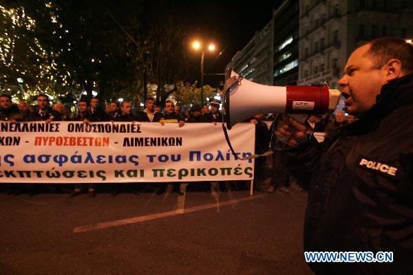 Greek police officers raise a banner that says 'Enough is enough with cuts on salaries' during a rally in front of the old parliament building in Athens, capital of Greece, Dec. 14, 2010. [Marios Lolos]Xinhua]
