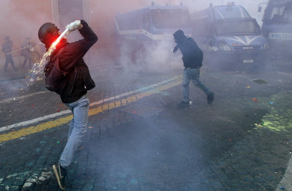 A demonstrator throws a flare during anti government clashes near parliament in Rome December 14, 2010. [China Daily/Agencies]