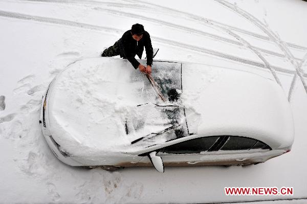 A man clears snow covering his car in Huaping Township of Enshi, central China&apos;s Hubei Province, Dec. 15, 2010. The first large scope of snowfall of this winter hit Hubei Province from Tuesday night.