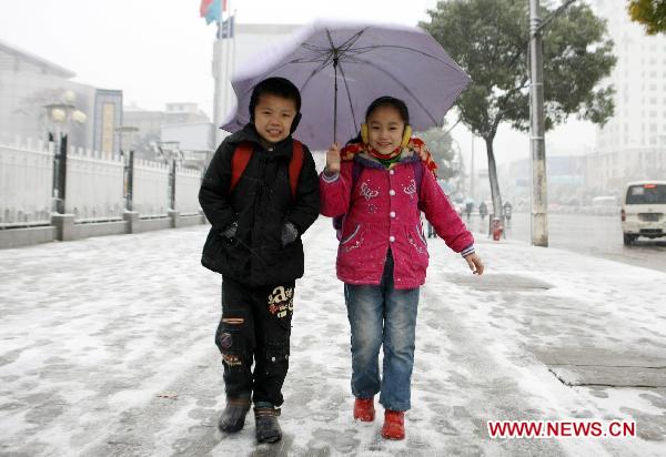 Pupils walk on a snow-covered road in Wuhan, capital of central China&apos;s Hubei Province, Dec. 15, 2010. The first large scope of snowfall of this winter hit Hubei Province from Tuesday night. 