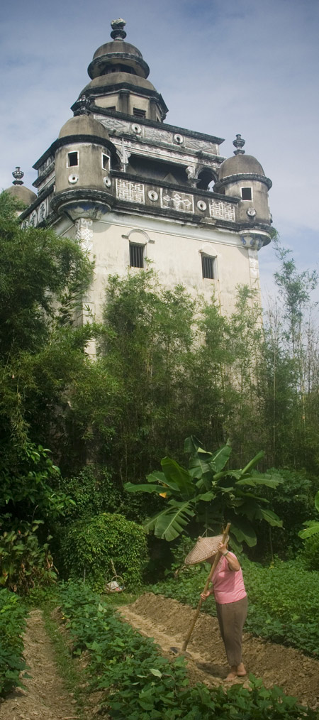 A farmer works under a Kaiping Dialou tower. The towers in Guangdong Province were chosen in 2007 as a UNESCO World Cultural Heritage Site. 