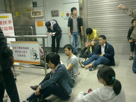 Dazed commuters sit on the ground of Guomao Station at Shenzhen's subway line No.1 Tuesday morning after a stampede triggered by a malfunctioning escalator left 25 people injured.