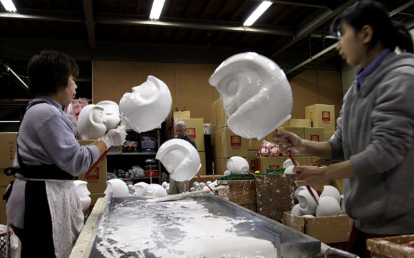 Staff members are busy processing the heads for Japanese tumblers in Takasaki, Japan, Dec 15, 2010. Tumblers are typical crafts in Japan, symbolizing good wishes. Takasaki, famous for its tumblers, embraces the peak time demand when New Year comes. [Xinhua]