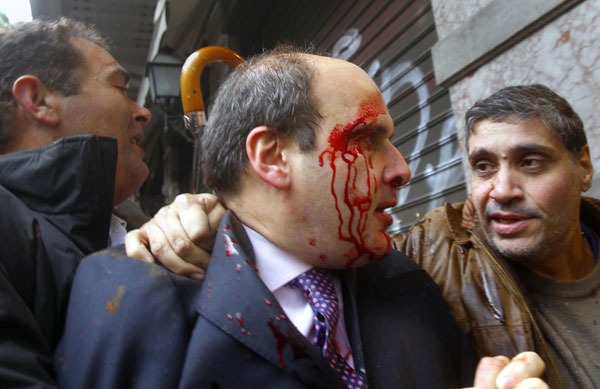 Former conservative minister of transportation Kostis Hatzidakis is covered with blood after about 200 leftists attacked him with stones and sticks, shouting: &apos;Thieves! Shame on you!&apos; in central Athens Dec 15, 2010. [China Daily/Agencies]