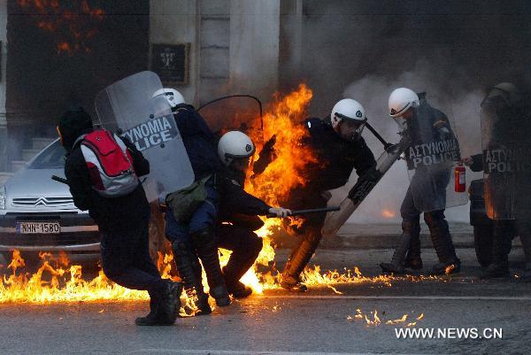 A demonstrator throw petrol bombs at riot police during a protest in Athens on December 15, 2010. Police fired teargas at protesters who threw dozens of petrol bombs outside parliament on Wednesday as Greek protests against government austerity measures escalated. [Marios Lolos/Xinhua]