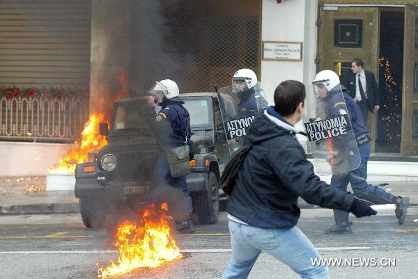 A demonstrator throw petrol bombs at riot police during a protest in Athens on December 15, 2010. Police fired teargas at protesters who threw dozens of petrol bombs outside parliament on Wednesday as Greek protests against government austerity measures escalated. [Marios Lolos/Xinhua]